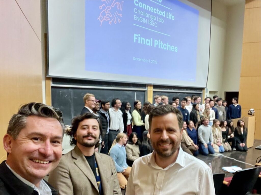 Giulio Pantano and peers take a selfie together on Final Pitch day of the Challenge Lab; they stand in front of the slides projected on the screen and a large group of people posing for a group photo