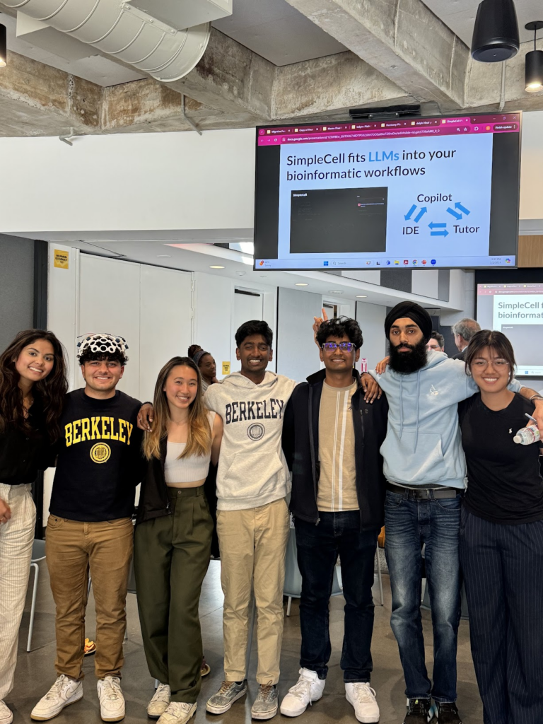 The SimpleCell team smiles for a group photo in front of their pitch deck slides.